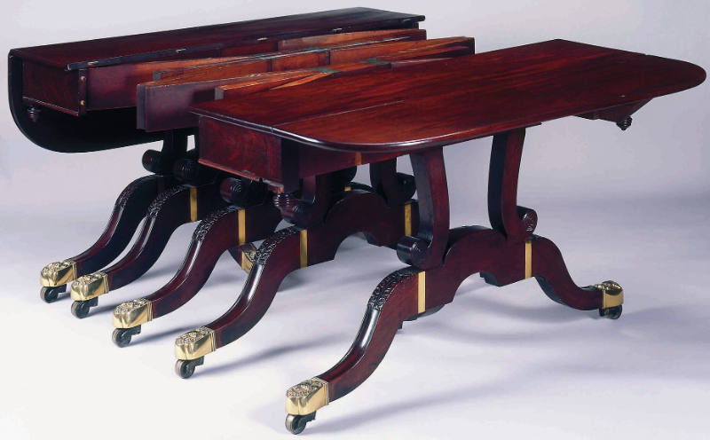 A mahogany extension dining table with five scrolled supports mounted on curule-style legs with…